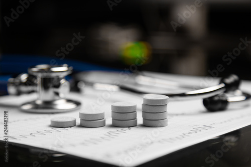 stethoscope and stairs from tablets lie on sheet with electrocardiogram