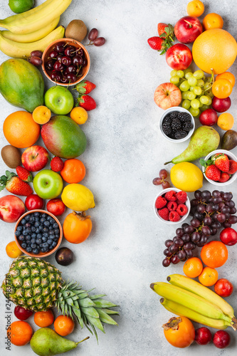 Fototapeta Naklejka Na Ścianę i Meble -  Healthy rainbow fruits berries background, strawberries raspberries oranges plums apples kiwis grapes blueberries mango persimmon on the white table, top view, copy space for text, selective focus