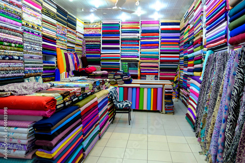 Rolls of fabric and textiles for sale stacked on shelves in shop,View of cloth rolls of different colors and patterns on shelves in fabric store  photo
