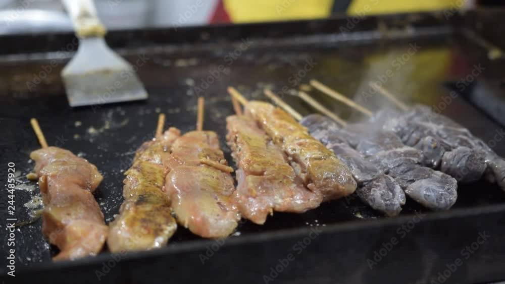 Skewers of meat and chicken being roasted on plate Skewers of meat and chicken being roasted on plate