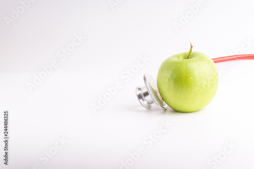 Green Apple with medical stethoscope isolated on white background for healthy eating. Selective focus and crop fragment. Healthy and copy space concept photo