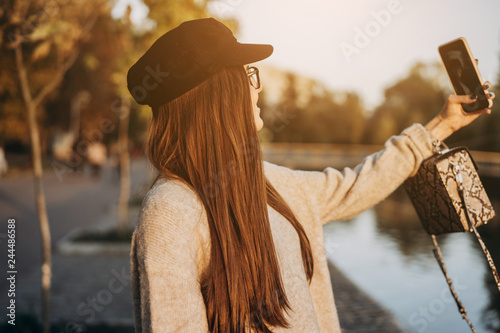 Cheerful young girl at the park, taking a selfie photo