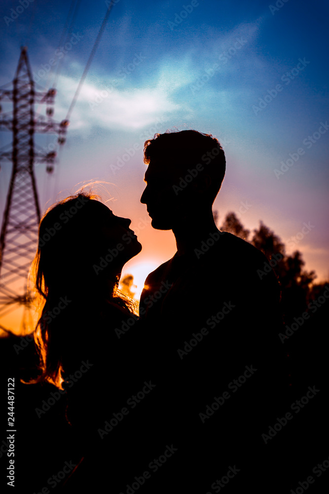 Silhouettes of a guy and girl in a field on a sunset background