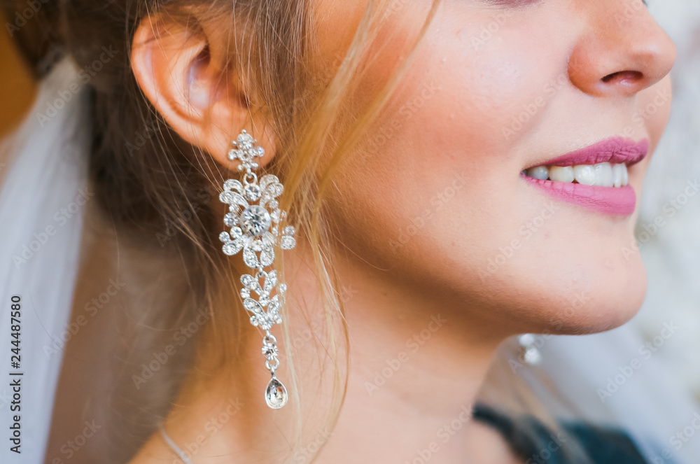 big beautiful earrings of the bride. The bride measures the beautiful jewelry
