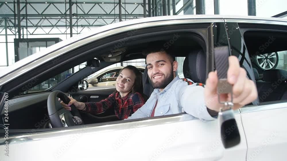 The concept of buying or renting a car. Young happy interracial couple with new car keys The concept of buying or renting a car. Young happy interracial couple with new car keys