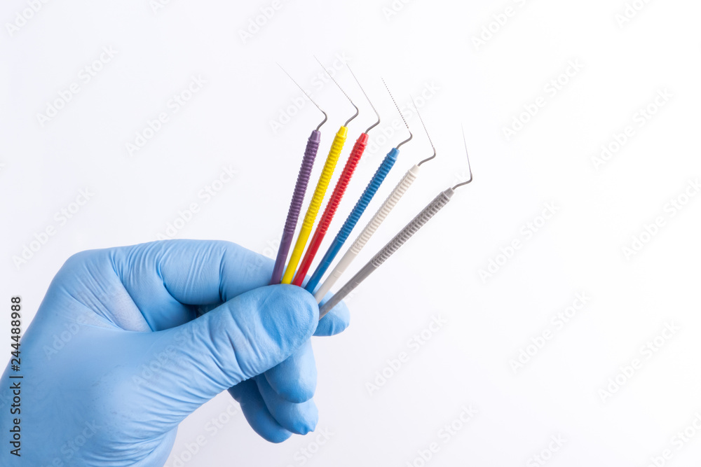 Endodontic files in a male dentist's hand. Doctor's hand in blue medical glove holding endodontic files.