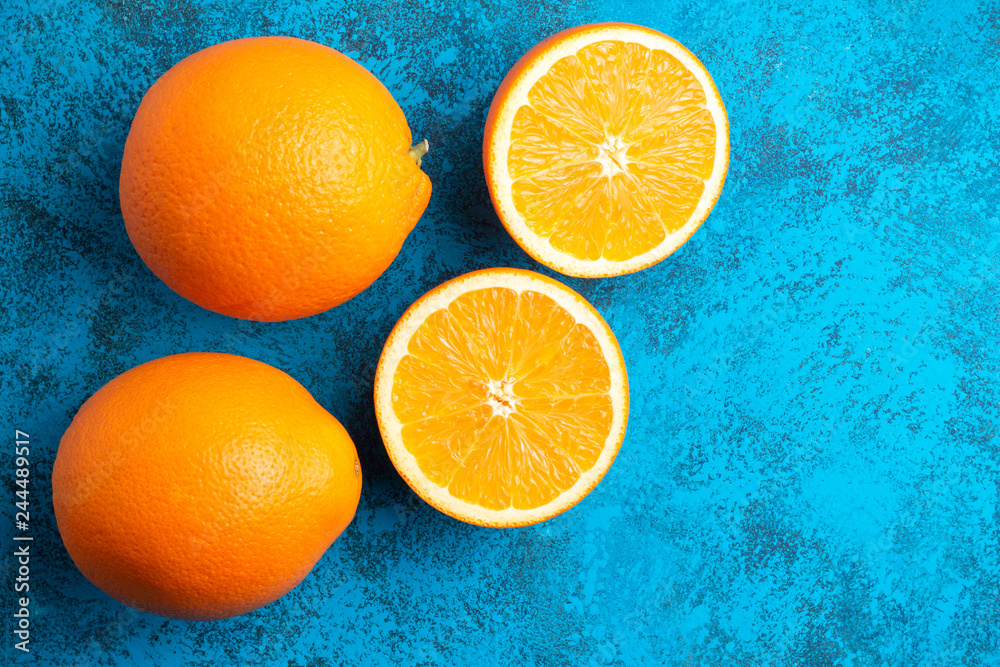 Orange halves and whole ripe citrus fruits on a blue background, top view Orange halves and whole ripe citrus fruits on a blue background, top view