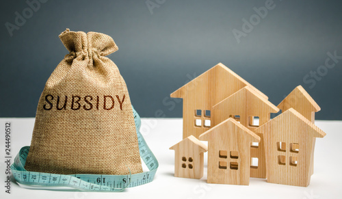 Money bag with the word Subsidy and wooden houses. Financial aid, support to the population. Cash grants, interest-free loans. Tax breaks, insurance, low-interest loans. Small minimal subsidy photo