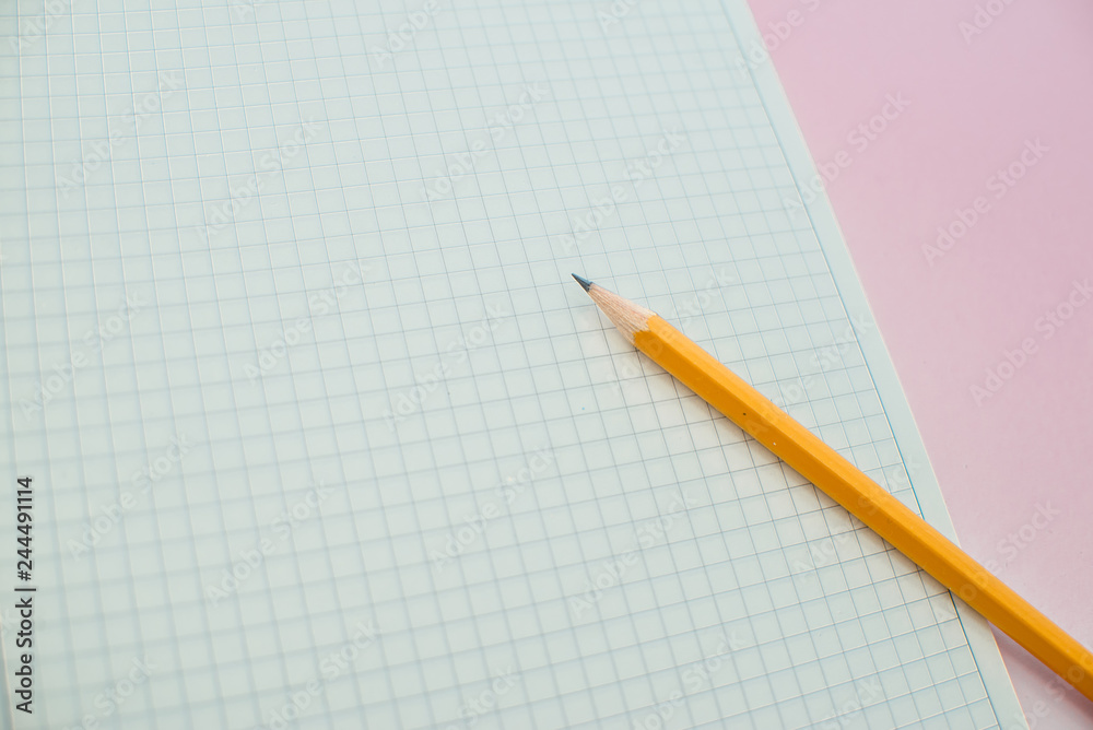 A pencil on a notebook in the linel. School supplies. White sketch book with orange pencil. Note book and pencil A pencil on a notebook in the linel. School supplies. White sketch book with orange pencil. Note book and pencil