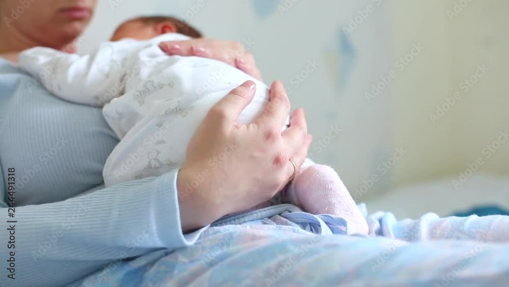 Young beautiful mother holding her cute baby who is sleeping on her mom's chest at home Young beautiful mother holding her cute baby who is sleeping on her mom's chest at home
