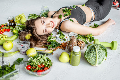 Beauty portrait of a sports woman surrounded by various healthy food lying on the floor. Healthy eating and sports lifestyle concept