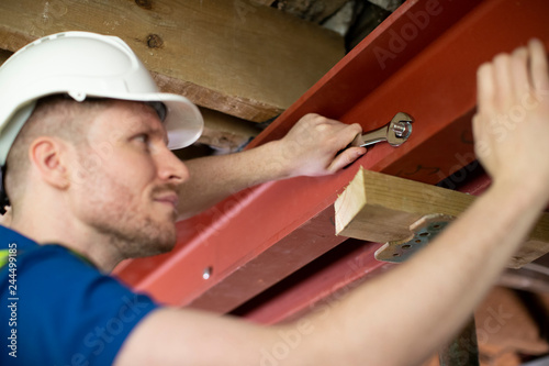 Construction Worker Fitting Steel Support Beam Into Renovated House Ceiling photo