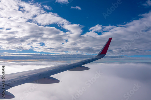 The wings of the plane flying over the white clouds in the daytime