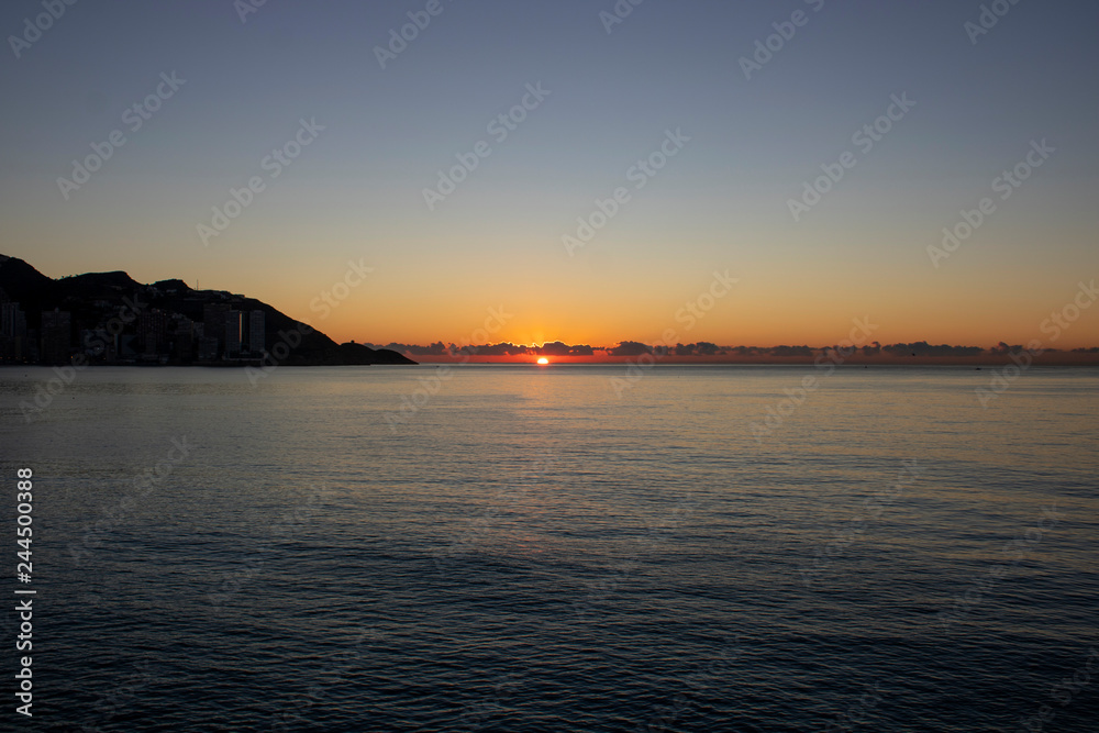 Beautiful morning sunrise over the sea showing yellow sun with a few clouds in the background, taken in Spain Costa Brava near Alicante and Benidorm 