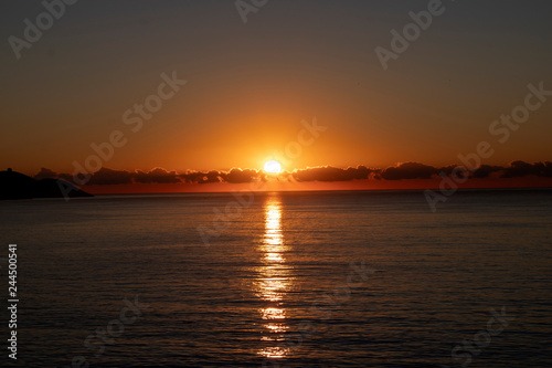 Beautiful morning sunrise over the sea showing yellow sun with a few clouds in the background, taken in Spain Costa Brava near Alicante and Benidorm  © Duncan