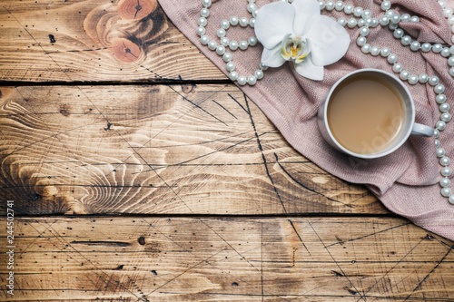 Orchid flower  cup of coffee and beads on a wooden table. Concept romance mood. Copy space and flat lay