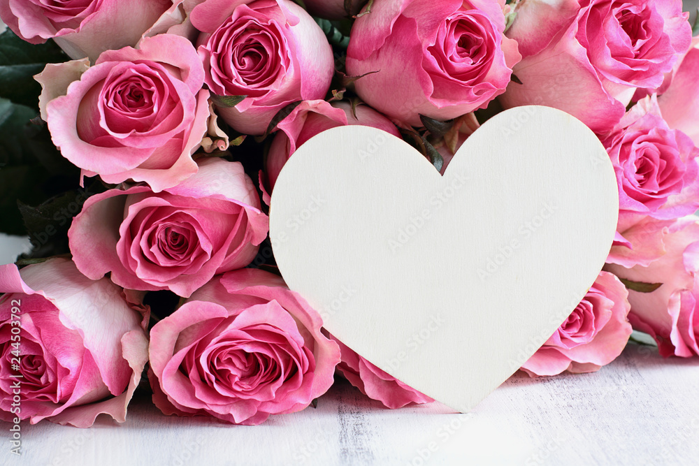 Beautiful retro soft pink rose flower background with wooden heart and room for text. Beautiful retro soft pink rose flower background with wooden heart and room for text.