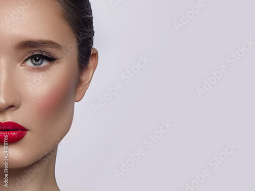 Half a beauty portrait with beautiful fashionable evening make-up, black jiggles on eyes and extremely long eyelashes. Pink lipstick on the lips. Cosmetology and spa facial skin care