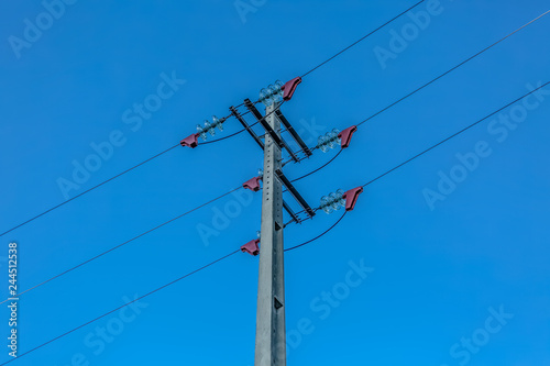 View of electricity pole and power lines with blue sky as background