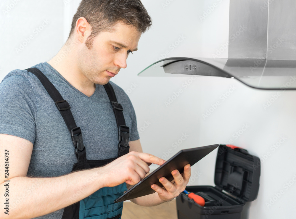 Obraz premium Handyman doing inspection of exhaust hood in the kitchen.