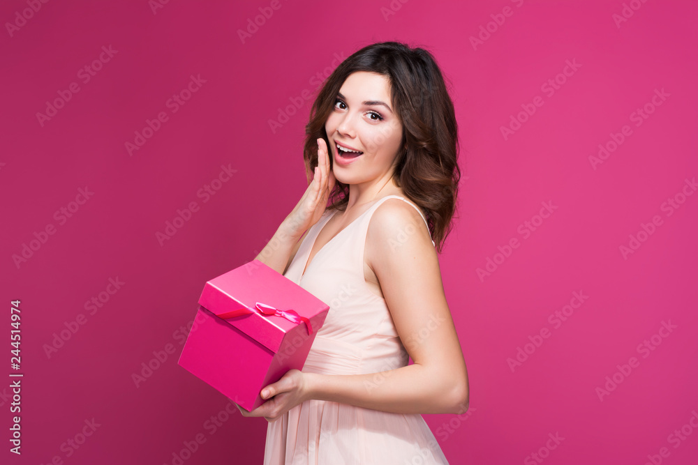 surprised brunette in a dress with a gift in hand surprised brunette in a dress with a gift in hand