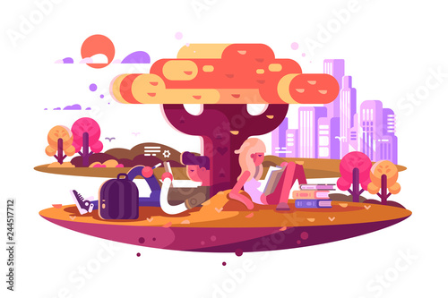 Young students sitting under tree and studying