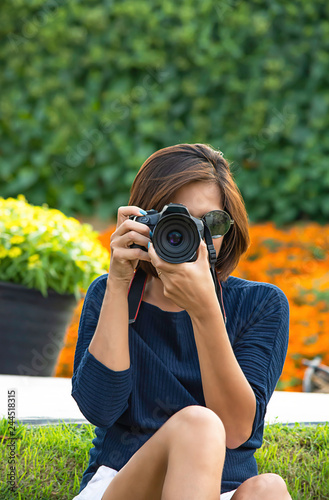 Hand woman holding the camera Taking pictures Background of trees and flowers