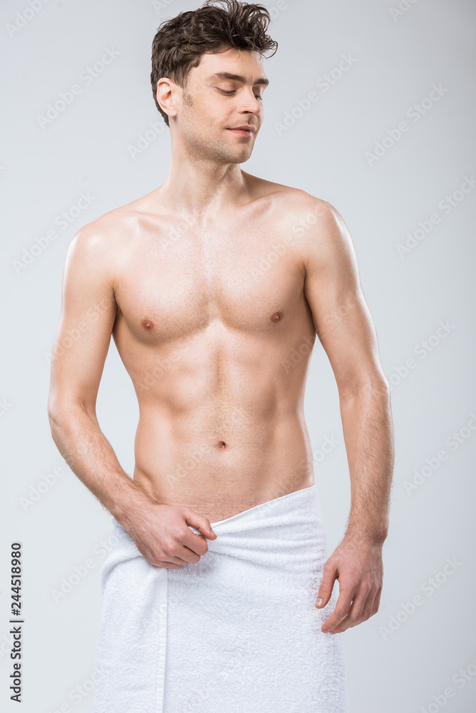 sexy shirtless smiling man posing in towel isolated on grey