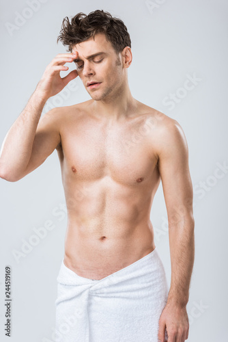 tired shirtless man posing in towel having headache isolated on grey