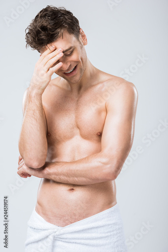 handsome sexy laughing man posing in towel isolated on grey
