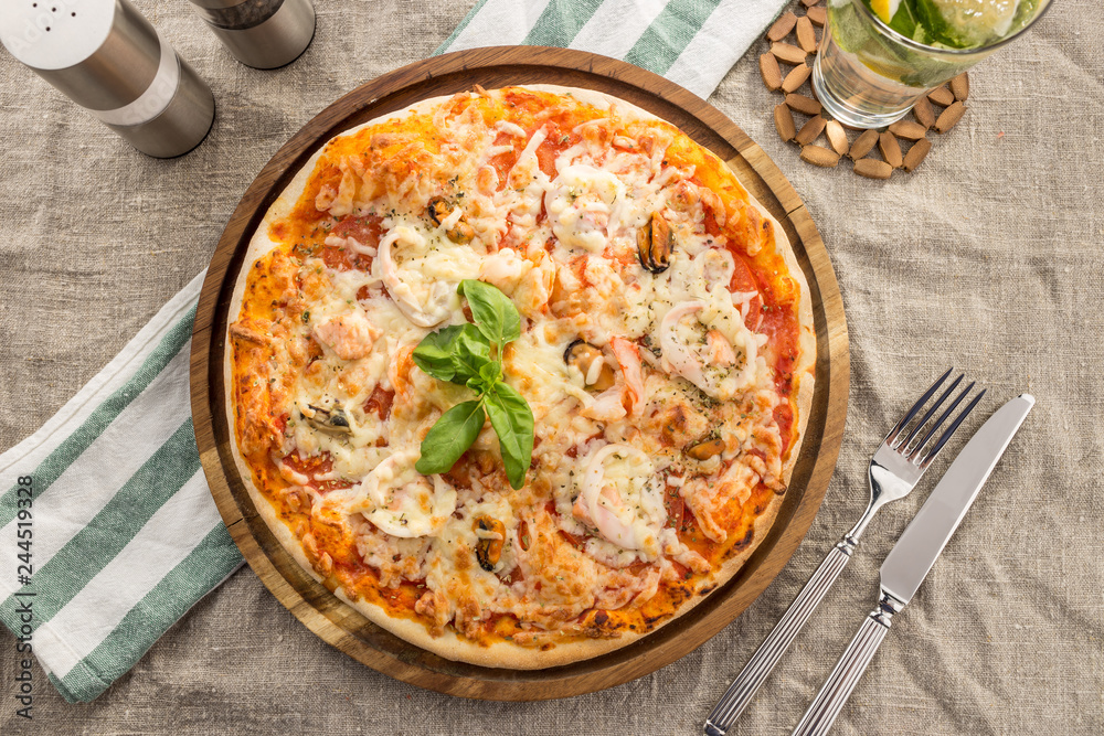 Pizza with seafood, mozzarella, mussels, octopus, squid, salmon, shrimp serves on the table Pizza with seafood, mozzarella, mussels, octopus, squid, salmon, shrimp serves on the table