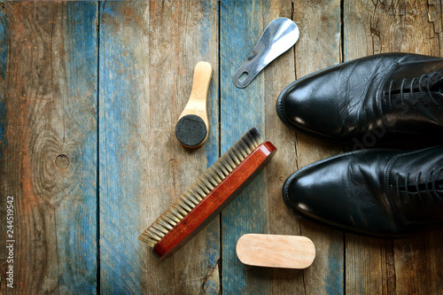 Shoes care concept background with leather shoes and accessories for cleaning. Wooden table with copy space. photo