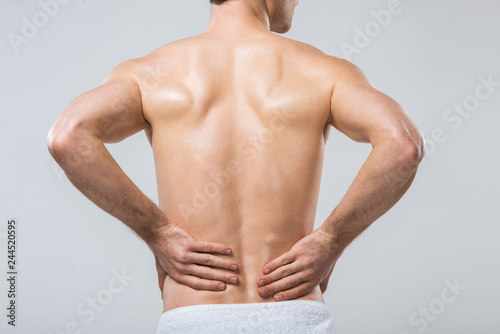 rear view of man having back pain, isolated on grey