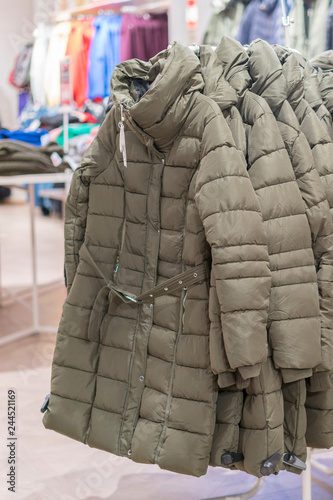 Set of clothes, coat on the rack clothing shop interior on background. Winter jackets in a store. vertical photo.