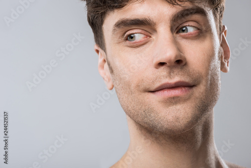 portrait of handsome young man looking away isolated on grey