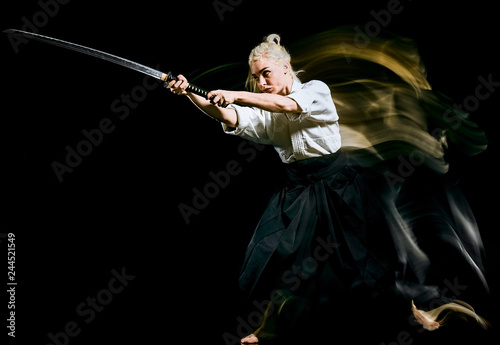 one bodokas fighters woman practicing Iaido  Kenjutsu  studio shot isolated on black background