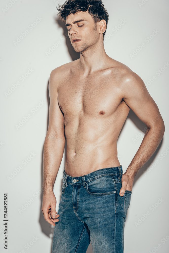 sexy shirtless fashionable man in jeans posing on grey