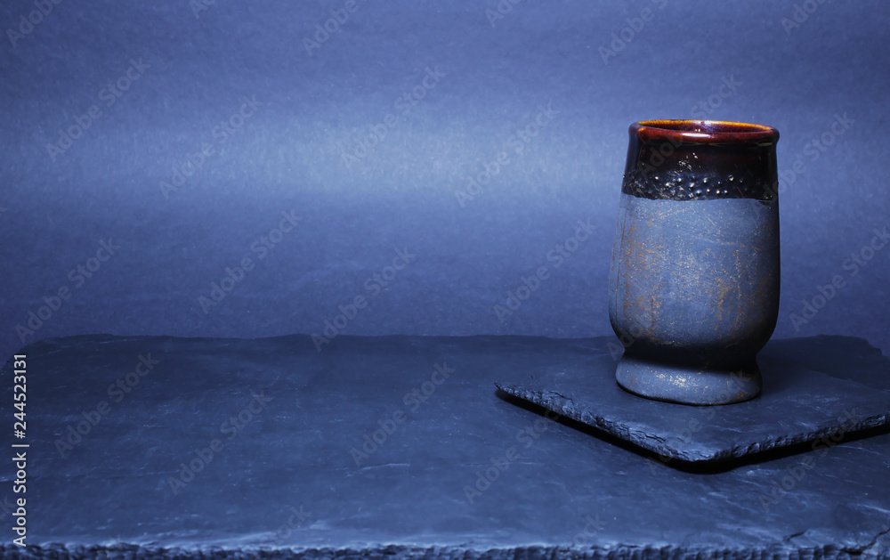 Naklejka premium View directly on the black slate plate and the cup holder on which there is a black ceramic cup. Copy space