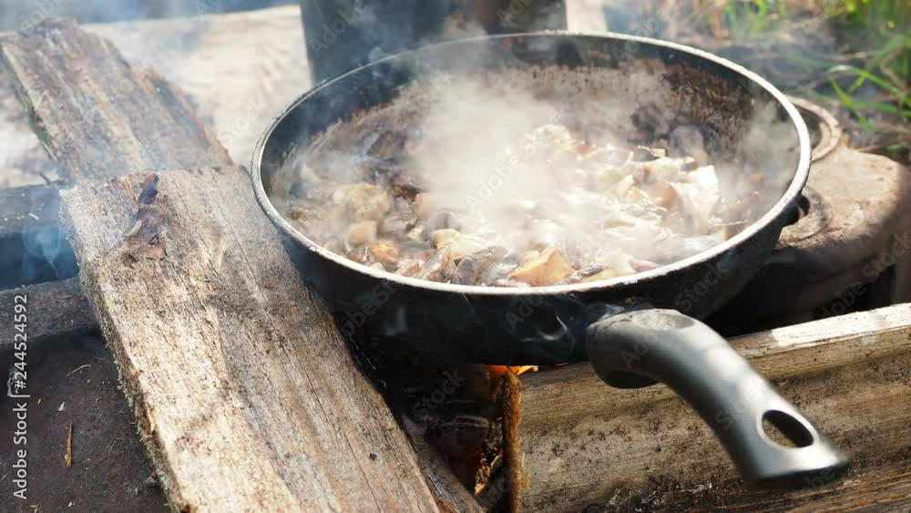 Cooking mushrooms on frying pan. Summer camping on beach. Kenozero national park, Russia. Cooking mushrooms on frying pan. Summer camping on beach. Kenozero national park, Russia.