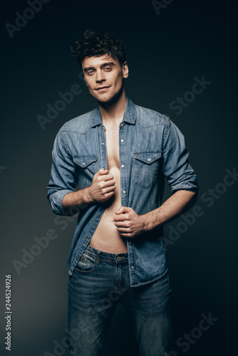 handsome muscular man posing in denim clothes isolated on dark grey