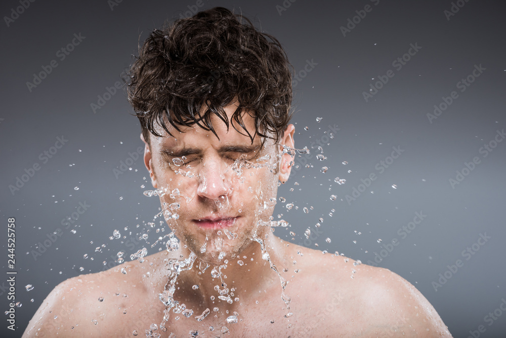 handsome man washing face with water drops, isolated on grey handsome man washing face with water drops, isolated on grey