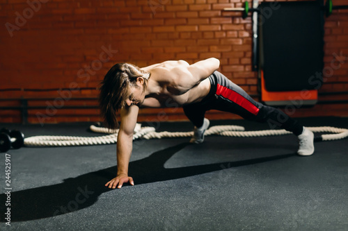Male young caucasian long hair model pushing off the floor strenuously. First training, start.