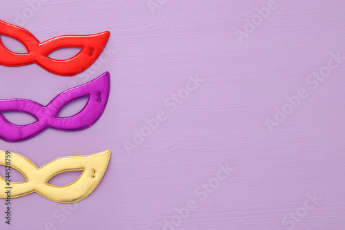 carnival party celebration concept with colorful masks over purple wooden background. Top view. Flat lay.
