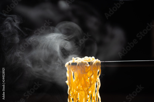Chopsticks noodles with steam and smoke  on black background. selective focus., korea, japan, china, Vietnam and Asian noodle junk food concept