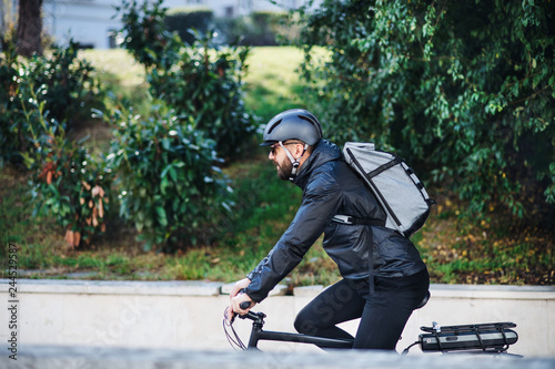 Male bicycle courier delivering packages in city. Copy space.