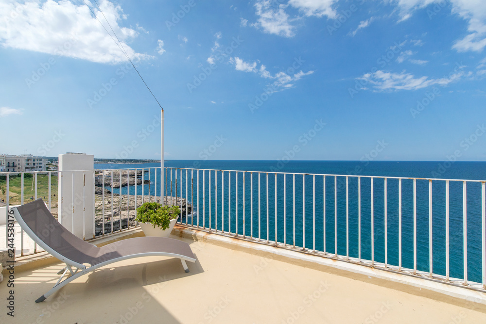 Fototapeta premium Four sunbathing beds layed on a villa roof next to the sea side. Beautiful view of blue sky and clean blue sea.