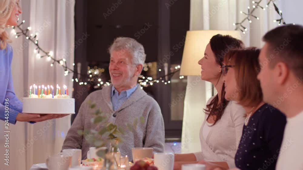 celebration and family concept - happy grandfather blowing candles on birthday cake at dinner party at home celebration and family concept - happy grandfather blowing candles on birthday cake at dinner party at home
