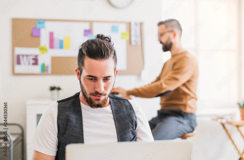 Two young male businesspeople with computer working in a modern office.