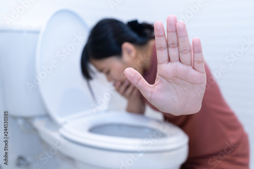 Woman hold hand and vomiting in toilet - sick concept photo