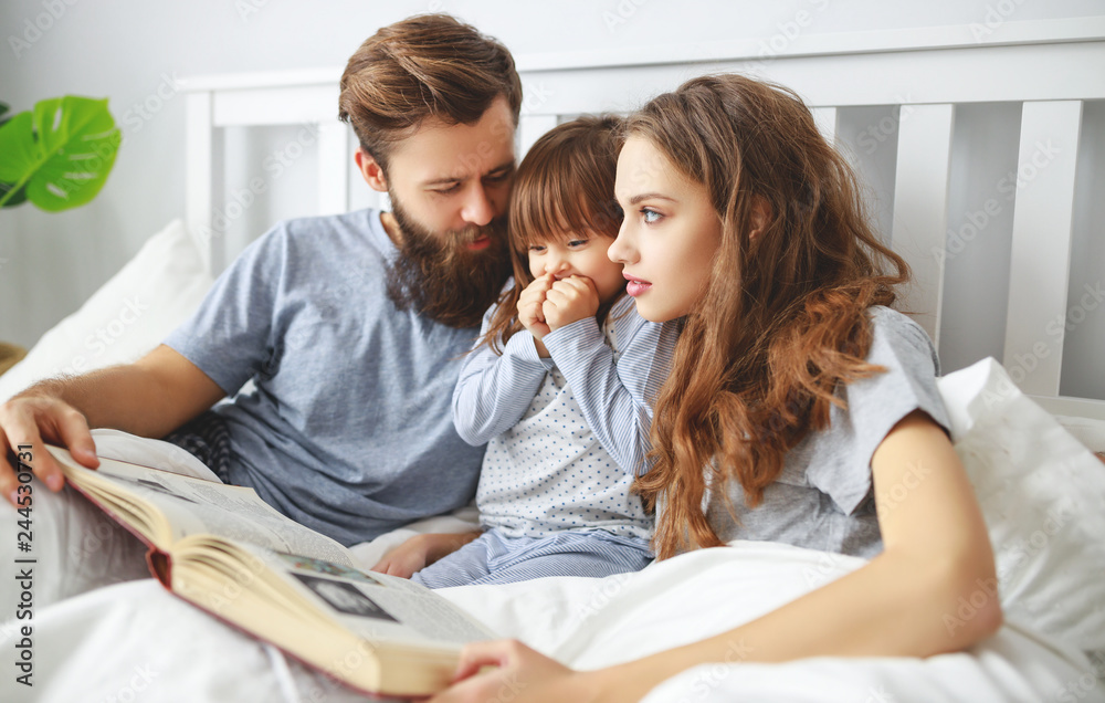 happy family mother, father and child read a book, a fairy tale in bed happy family mother, father and child read a book, a fairy tale in bed